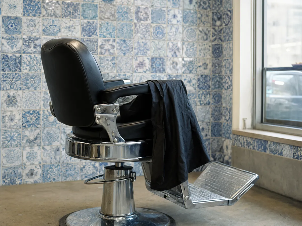 A black leather barber chair in front of a wall of blue and white tiles